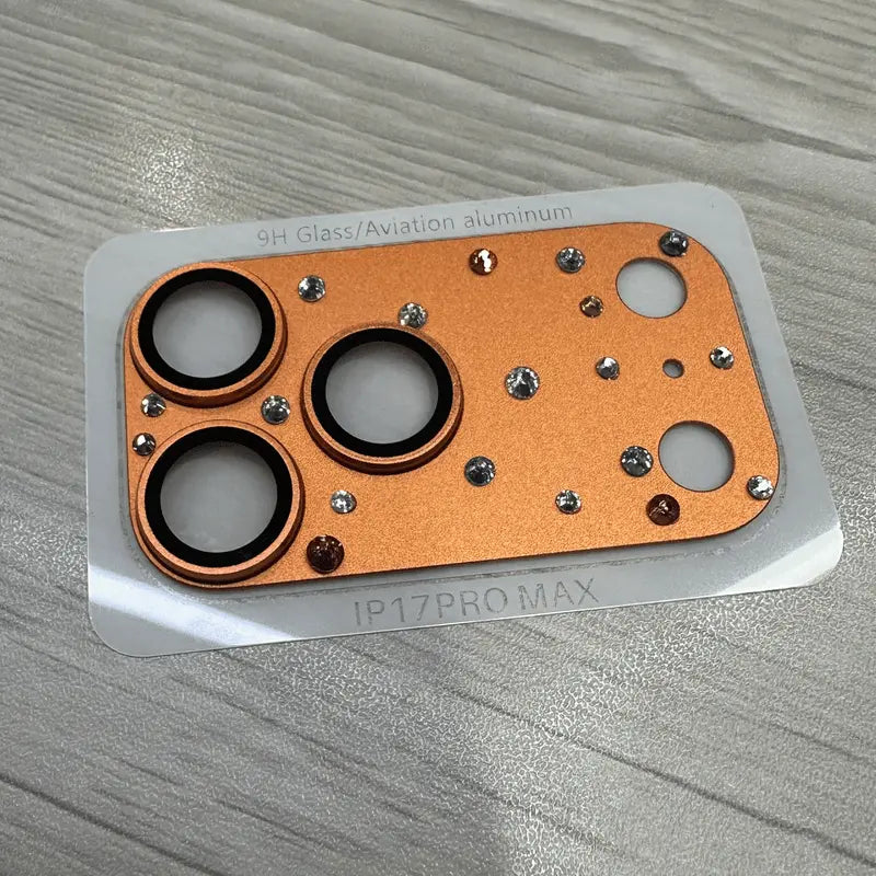 Orange diamond camera protector displayed on backing labeled iPhone 17 Pro Max