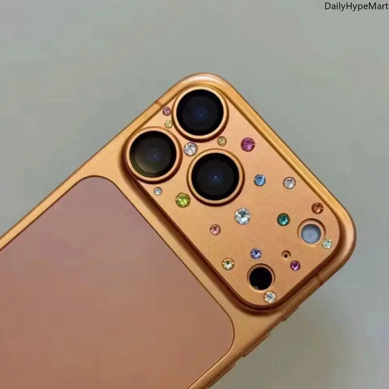 Smooth orange camera lens casing with colorful decorative diamond-like accents installed on an iPhone