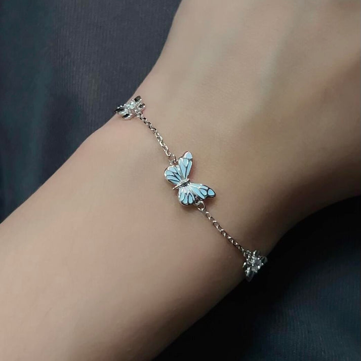 Luminous blue butterfly bracelet worn on wrist in daylight